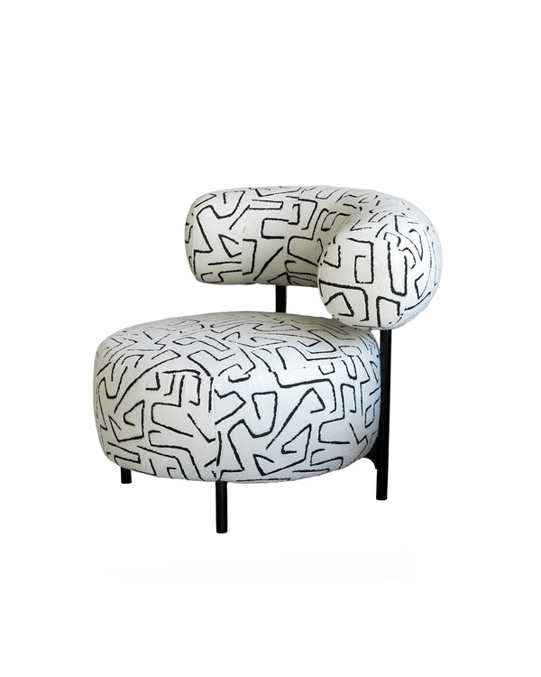 Contemporary armchair with curved backrest and patterned upholstery – side angle.